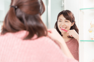 woman brushing her teeth in the mirror